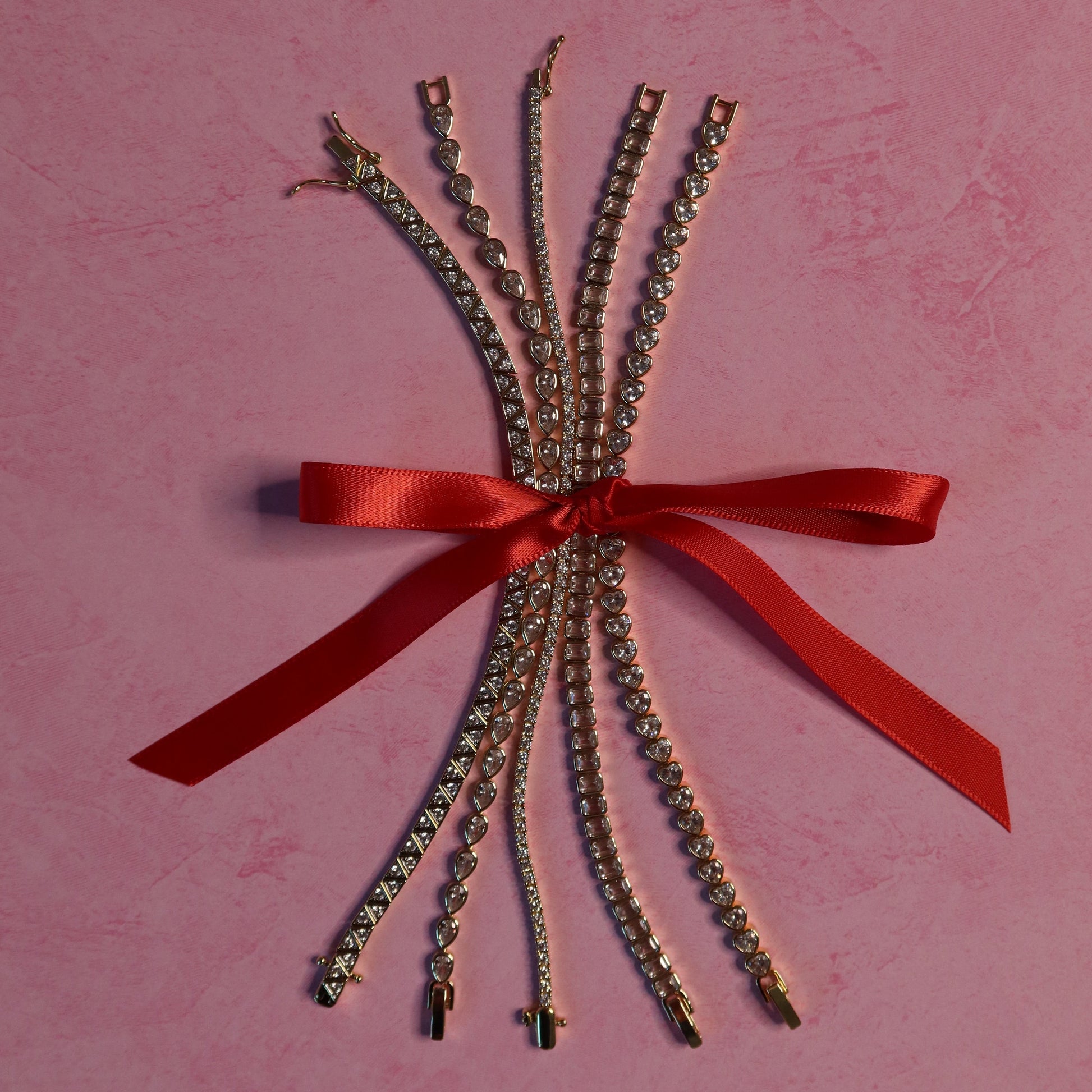 Bouquet of gold chains with a red ribbon on a pink background